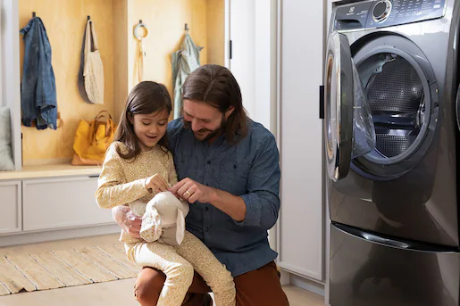 Father and daughter holding stuff animal plushy after it has been out of the dryer